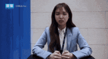 a woman in a blue suit is sitting in front of a wall