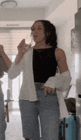 a woman in a black tank top is drinking a glass of wine