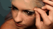 a woman with long eyelashes is applying makeup to her face