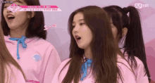 a group of girls wearing pink sweatshirts are standing in front of a mnet logo ..