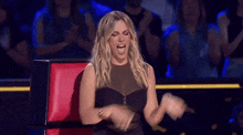 a woman in a black dress is sitting on a red chair with her mouth open