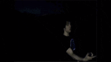 a young man wearing a black champion shirt is standing in the dark .