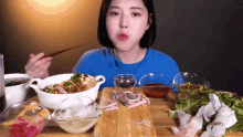 a woman in a blue shirt is eating a bowl of food