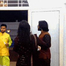 a man in a yellow vest stands next to a woman in a purple dress