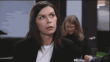 a woman in a black suit is making a funny face