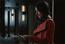 a woman in a red coat looking at her phone