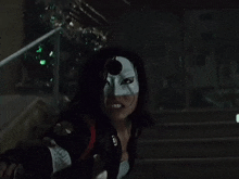 a woman wearing a mask is standing on a set of stairs holding a sword .