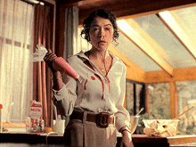 a woman in a white shirt is holding a pink bottle in front of a carton of milk