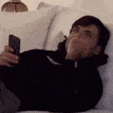 a man is laying on a couch holding a cell phone in his hand .