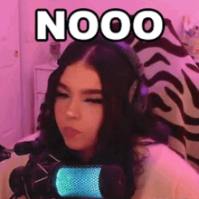 a woman wearing headphones is sitting in front of a microphone with the word nooo on it .