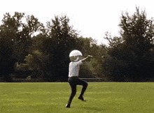 a person wearing a helmet is standing in a field with a frisbee in their hand .