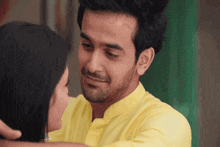 a man in a yellow shirt is hugging a woman in a black dress