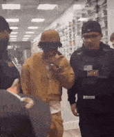 a man wearing a vest that says agent is being escorted by a police officer