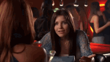a woman in a black tank top stands in a room with other women