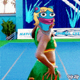 a cheerleader with a frog face on her head stands in front of a sign that says national cheer