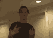 a man in a black shirt is giving the middle finger in a dark room
