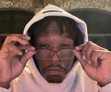 a man wearing a hoodie and glasses is making a face