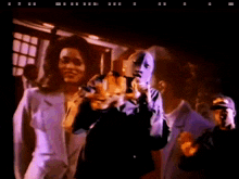 a group of people standing in a dark room with a man wearing a mask