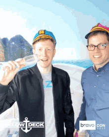 two men pose for a photo in front of a screen that says below deck on it