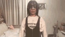 a woman wearing a mystic noir shirt is standing in a bedroom