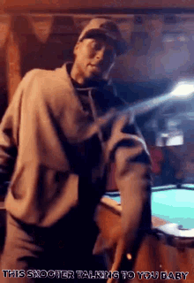 a man is standing in front of a pool table with the words " this shooter talking to you baby " written below him
