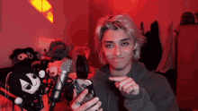 a young man is standing in front of a microphone with a stuffed animal behind him