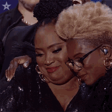 two women are hugging each other while wearing glasses and earrings .