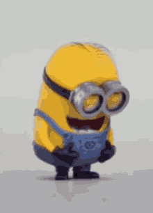 a yellow minion wearing goggles and overalls is laughing .