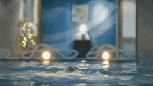 a person is swimming in a pool with candles and lights