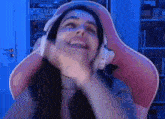 a woman is sitting in a pink chair wearing headphones and laughing .