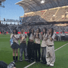 a group of girls are posing for a picture on a soccer field in front of a stadium that has the word zoo on it