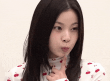 a woman wearing a white shirt with red cherries on it