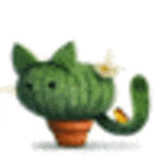 a cat shaped cactus in a pot with a yellow flower on its tail .