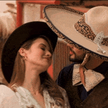 a man wearing a sombrero looks at a woman wearing earrings