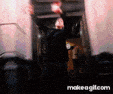 a man in a suit is dancing in front of a make a gif.com logo