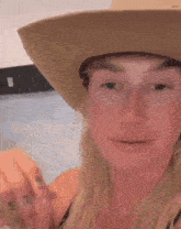 a woman wearing a cowboy hat and earrings is smiling .