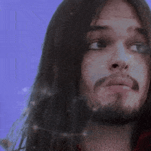 a man with long hair and a beard has a purple background