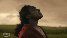 a woman in a red hoodie is standing in a field with the word prime on the bottom right