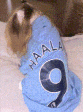 a dog is wearing a blue haala jersey with the number 9 on it