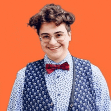 a young man wearing a vest and a bow tie smiles for the camera