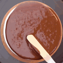 a wooden spoon is sticking out of a bowl of chocolate sauce