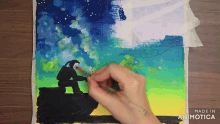 a person is painting a picture with the words made in animatica on the bottom right