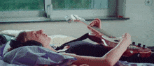 a woman is laying on a bed playing a guitar and listening to music