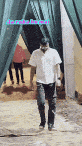 a man in a white shirt is walking in front of a green curtain that says aa raha hai