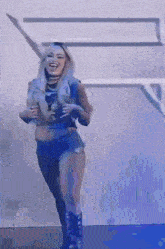 a woman in a crop top and shorts is dancing in front of a white wall .