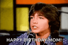a young man is talking into a microphone and saying happy birthday mom .