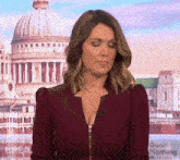 a woman in a burgundy jacket is standing in front of a dome .