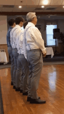 a group of men are standing in a row wearing suspenders and white shirts
