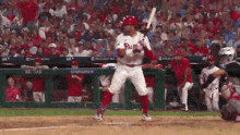 a baseball player in a phillies uniform is swinging a bat at a ball .