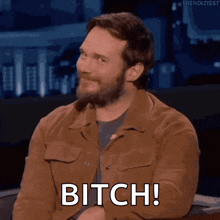 a man with a beard is saying bitch while sitting in a chair